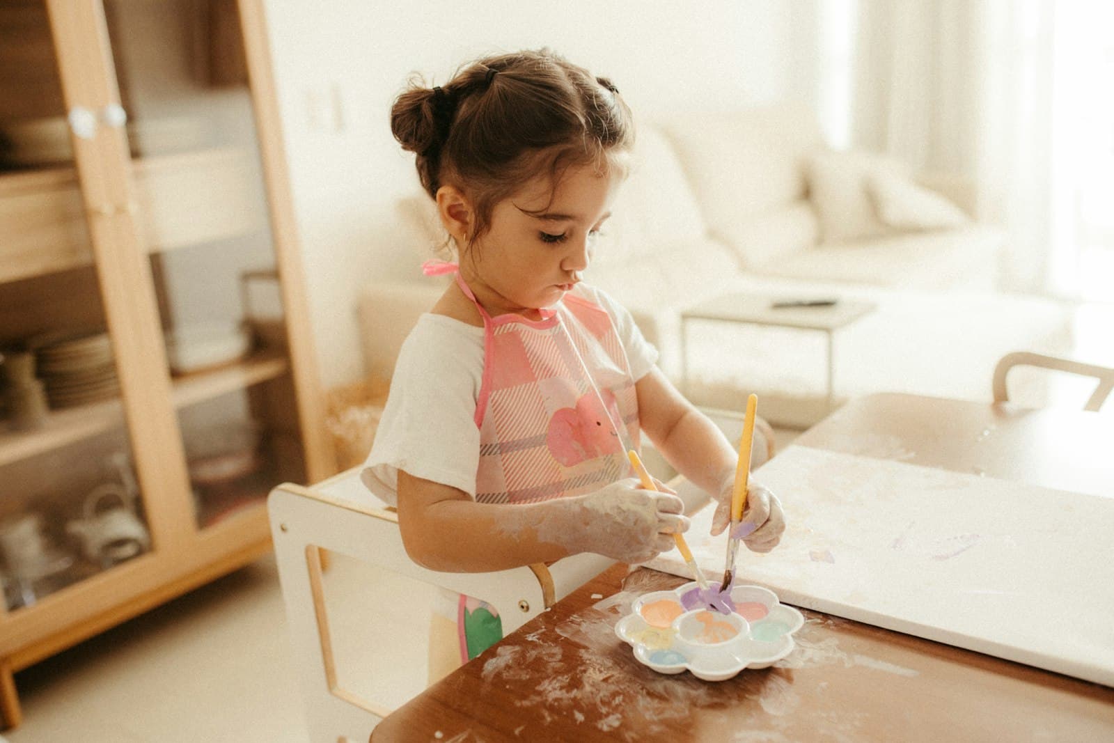 Masada sulu boyayla resim yapan küçük bir kız